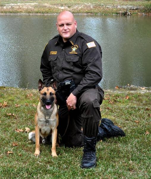 Deputy Bradley Skipworth and K-9 Bono in front of a lake.