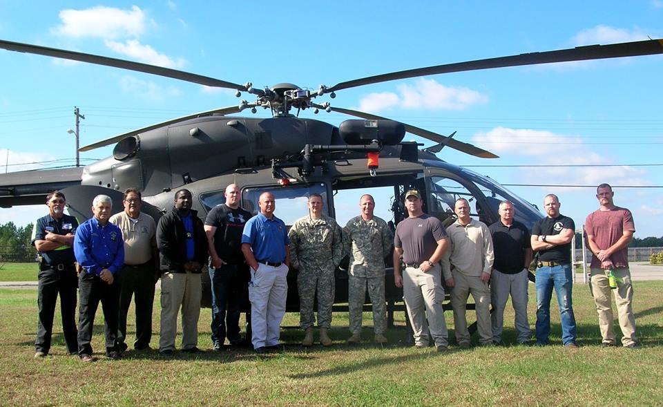 A group of individuals standing in front of a helicopter. From left to right:  Andy Wayne Smith a member of Colbert County Rescue, Sheriff Frank Williamson, Chief Jim Heffernan, Dep. Durand Prince, Dep. Wesley Withers, Sgt. Dan Coggins, (two pilots whose names we are protecting due to their sensitive line of work), Dep. Joseph Niedson, Dep. Johnny White, Dep. Jim Berryman, Dep. Jeremy Edgmon, and Dep. Marc Moore. 